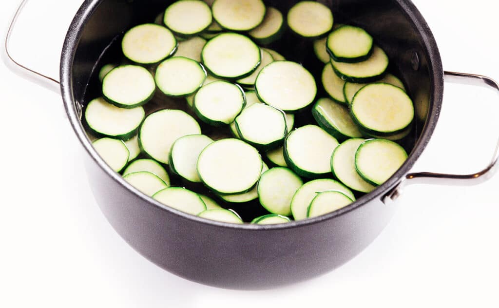 Zucchini slices in a stockpot of water.
