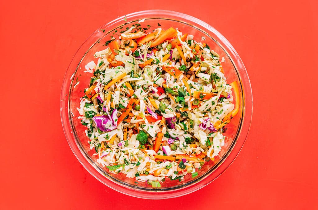 A clear glass bowl filled with freshly mixed Thai cabbage salad