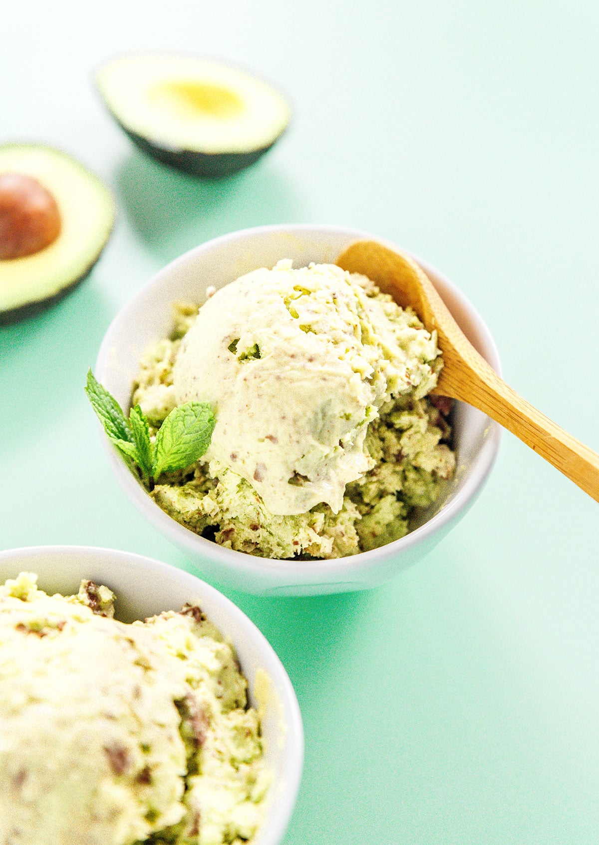 Mint chocolate avocado ice cream in a bowl with a wooden spoon.