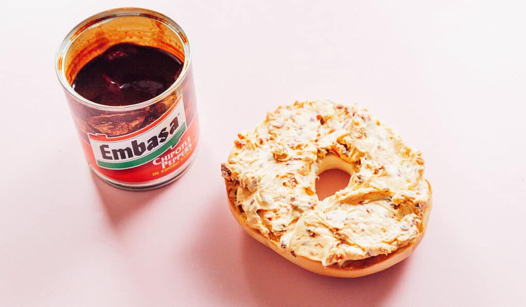 Chipotle pepper cream cheese spread on a bagel half.