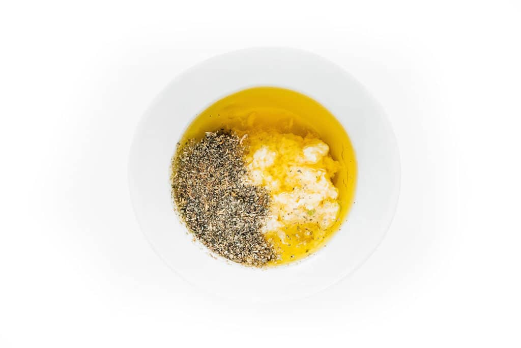 Garlic and herb marinade in a small white bowl.