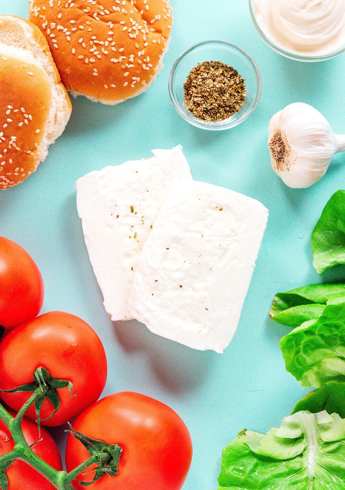 Ingredients for these burgers including halloumi cheese, lettuce, oregano, garlic, buns, tomato, mayo, and salt and pepper.