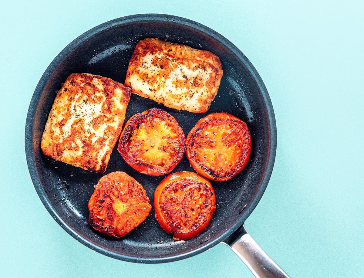 Grilling pan with charred tomatoes and halloumi patties.