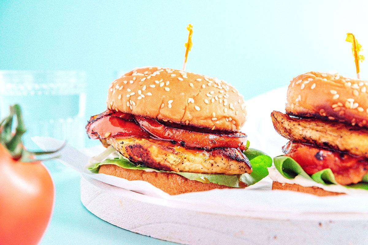 Two Halloumi Burgers stacked with lettuce, mayo, halloumi, tomato, and sesame buns.