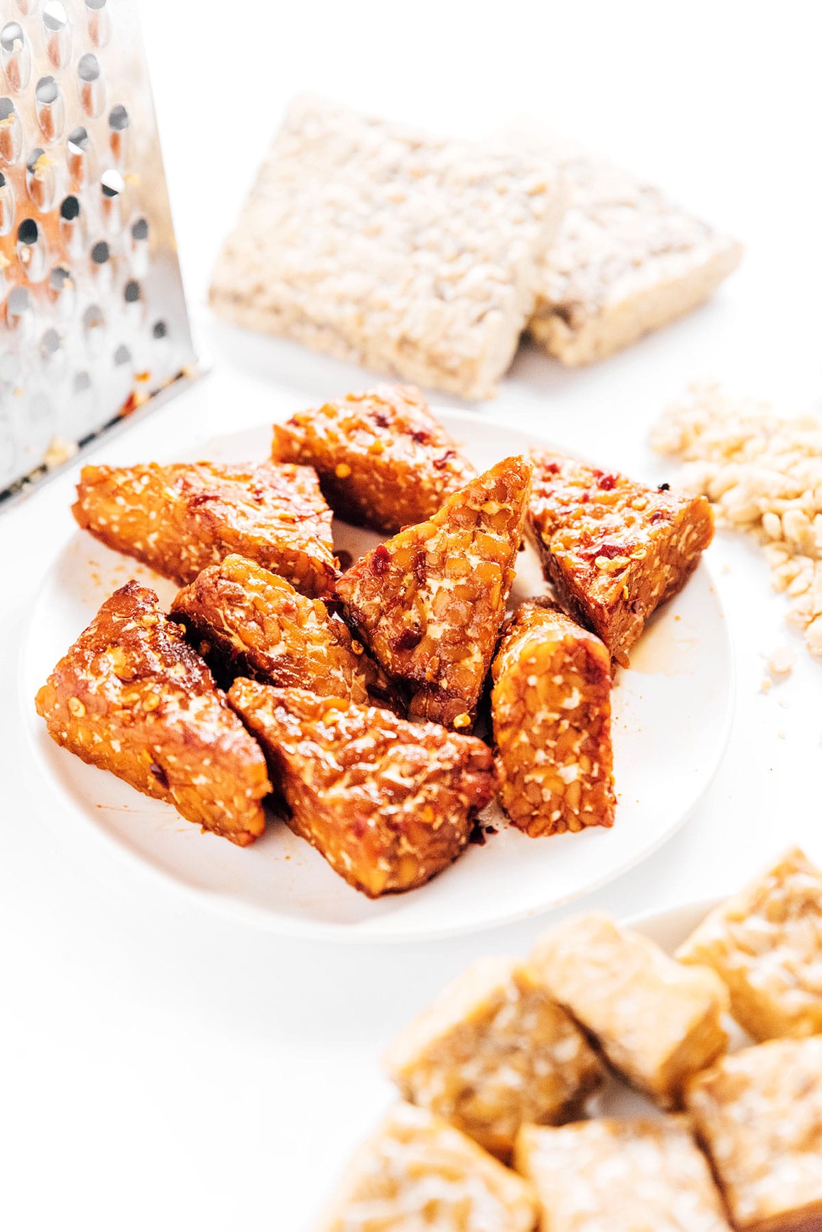 Marinated and cooked tempeh triangles on a white plate.
