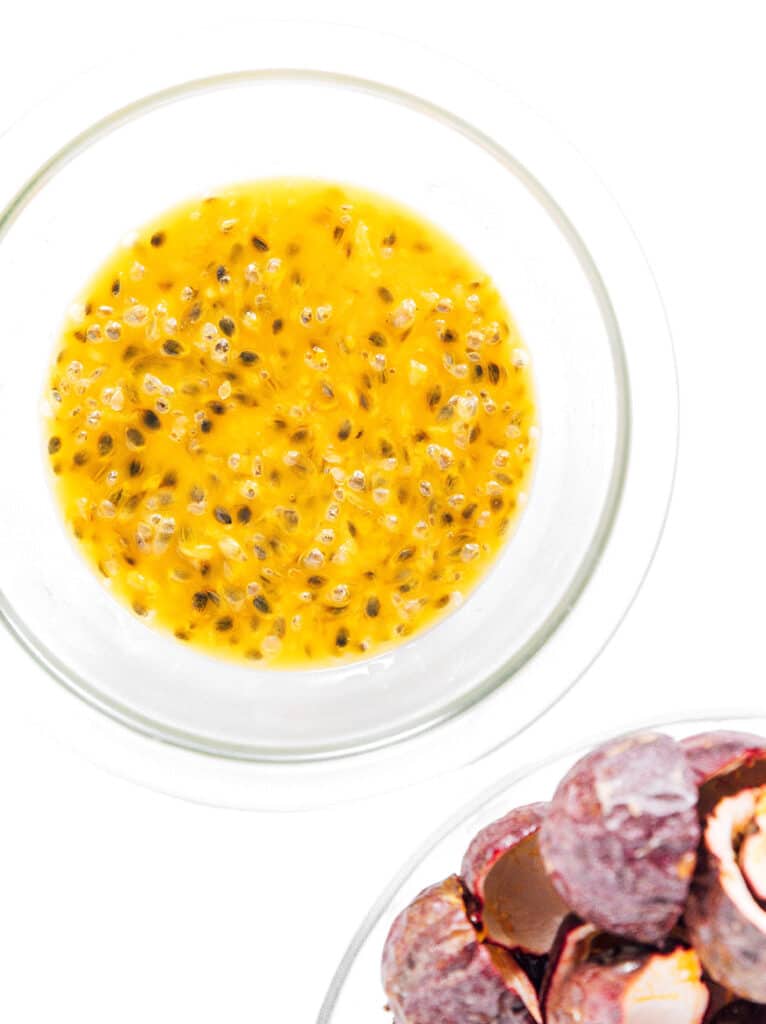 A bowl of passion fruit puree next to a bowl of empty passion fruit shells.
