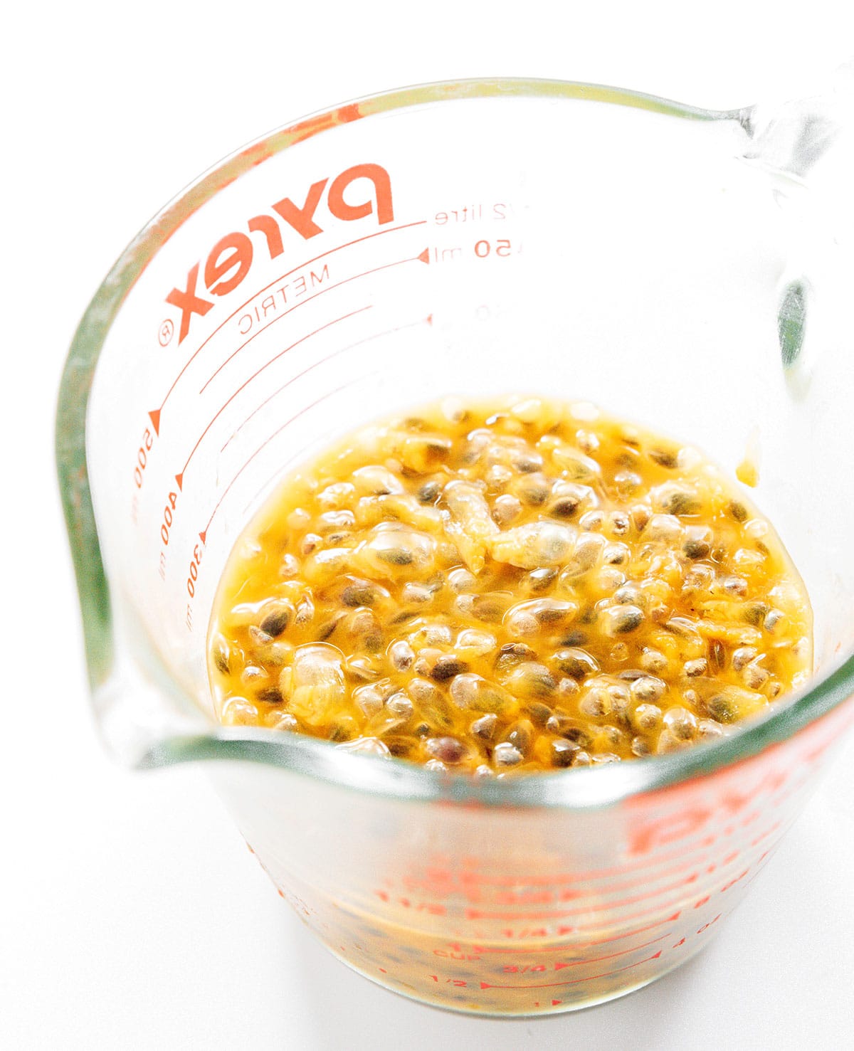 Passion fruit pulp in a glass measuring cup.