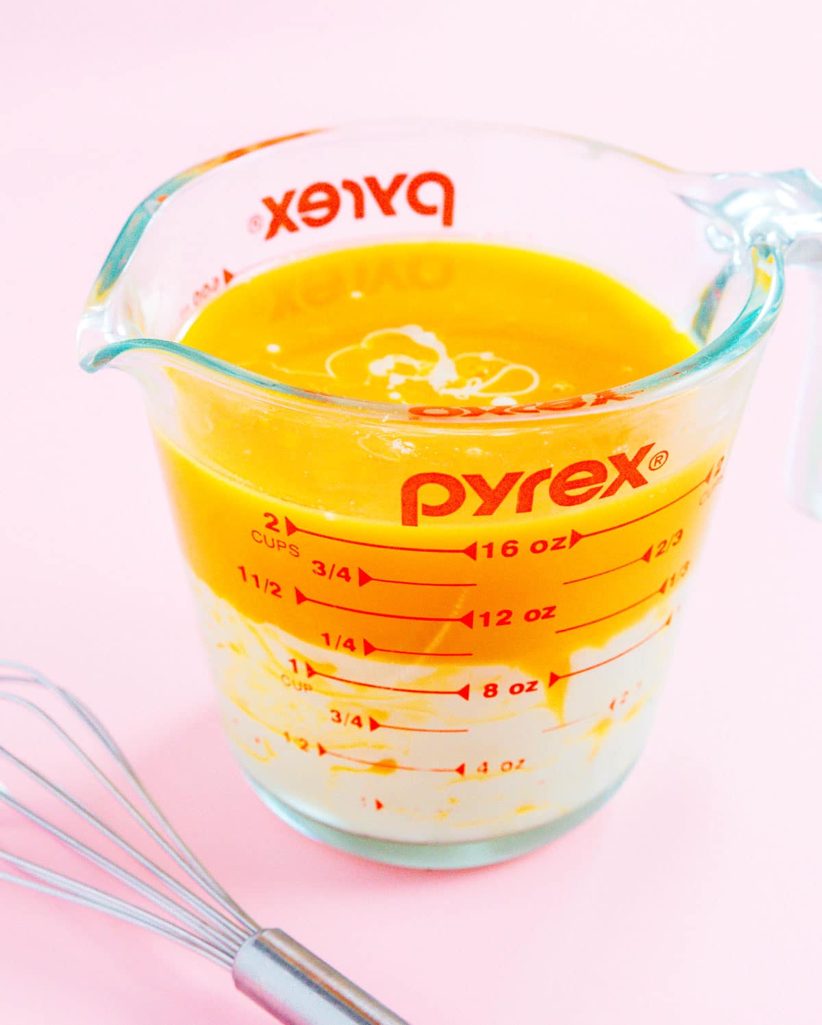 Passion fruit puree and condensed milk in a glass measuring cup.