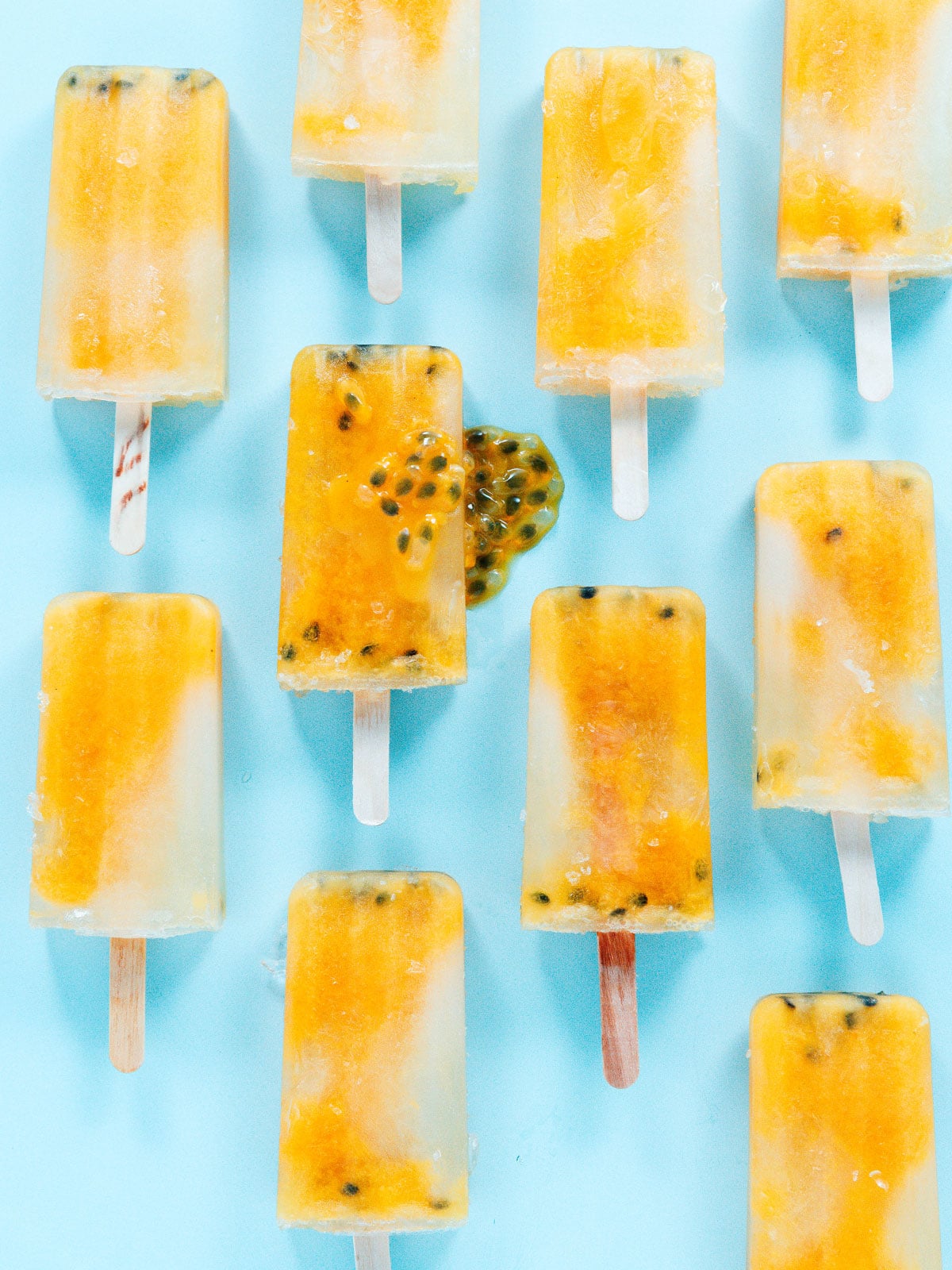 Multiple passion fruit popsicles on a blue background.