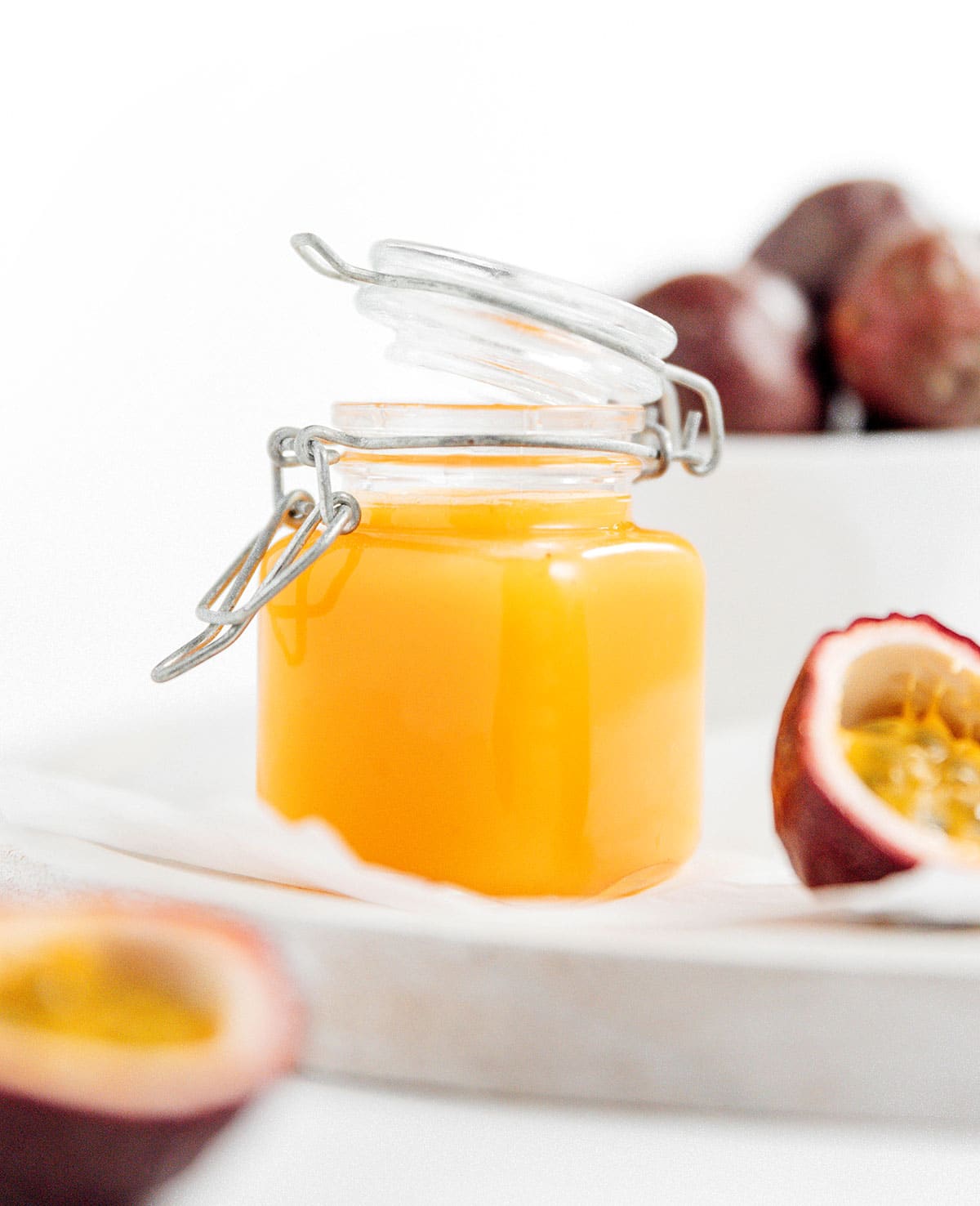 A cut open passion fruit next to a small jar of passion fruit puree.