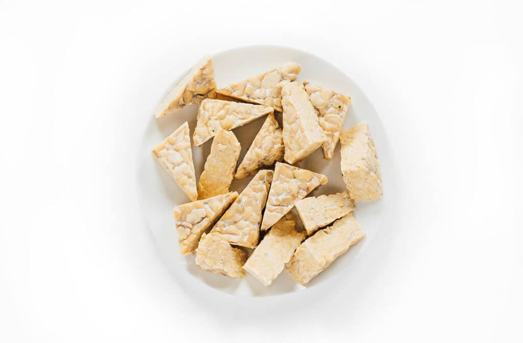Plain tempeh triangles on a white dinner plate.