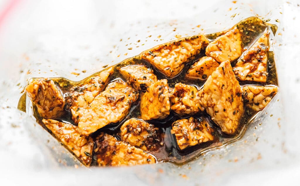 Balsamic herb marinade poured over tempeh slices in a zippered bag.