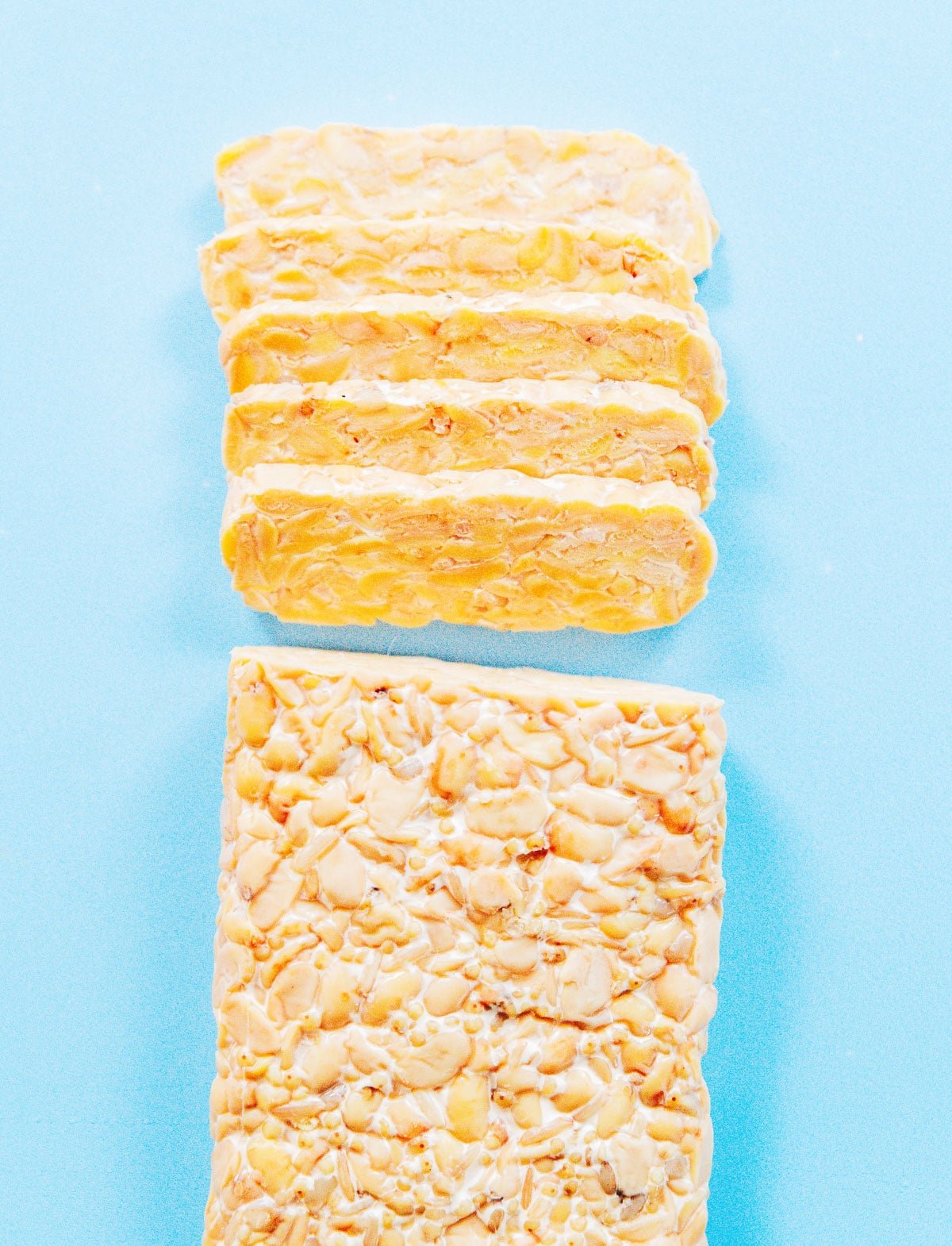 A slab of tempeh with narrow slices cut off one end.