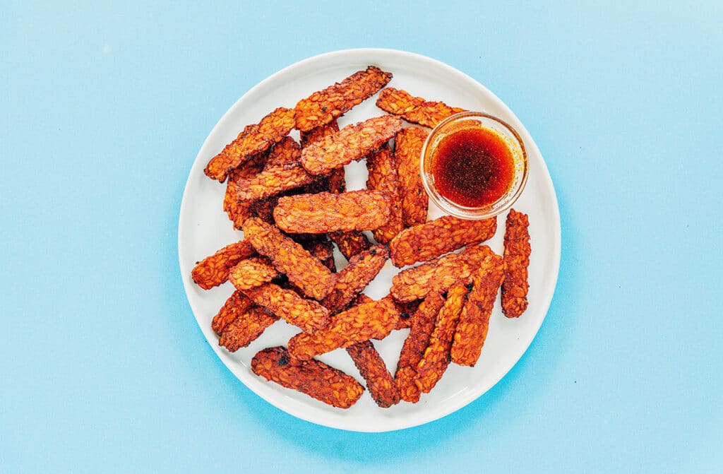 Tempeh slices fried like bacon on a white serving platter.