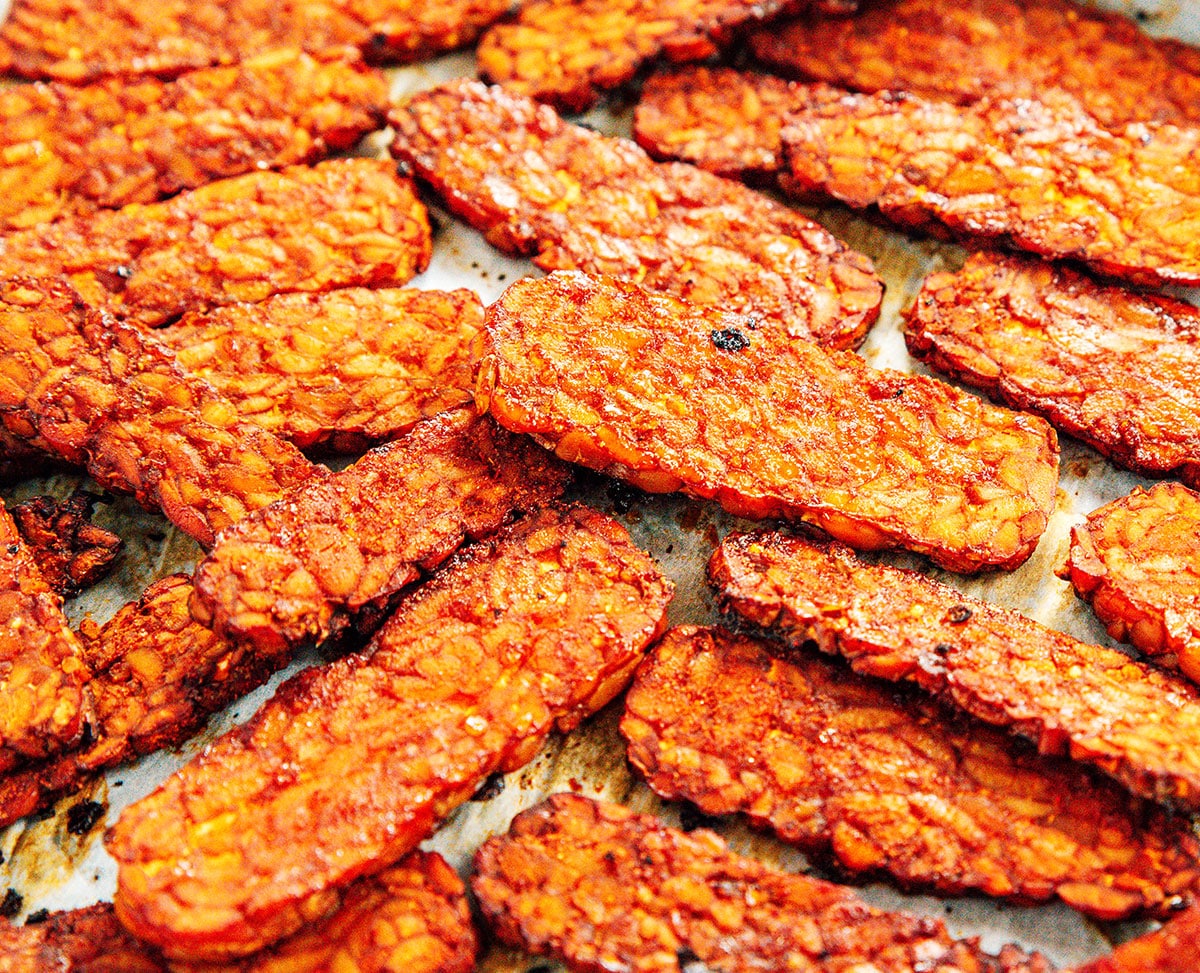 Smoky bacon flavored tempeh slices baked on a cookie sheet.