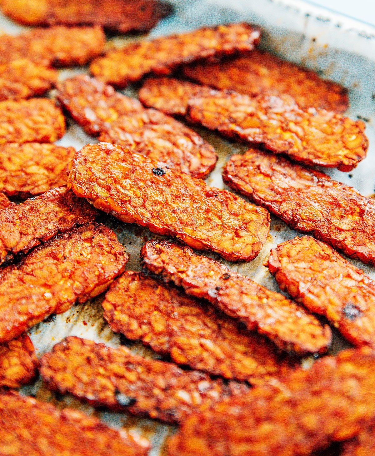 Smoky bacon flavored tempeh slices baked on a cookie sheet.