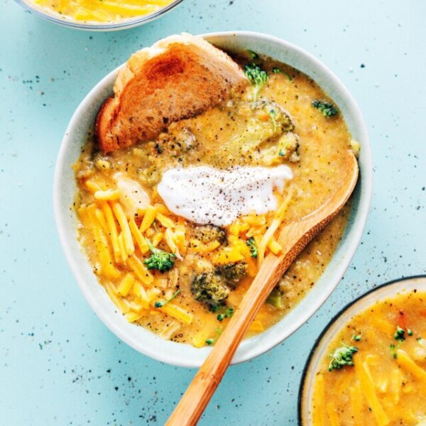 Blue bowl of broccoli cauliflower soup with a wooden spoon
