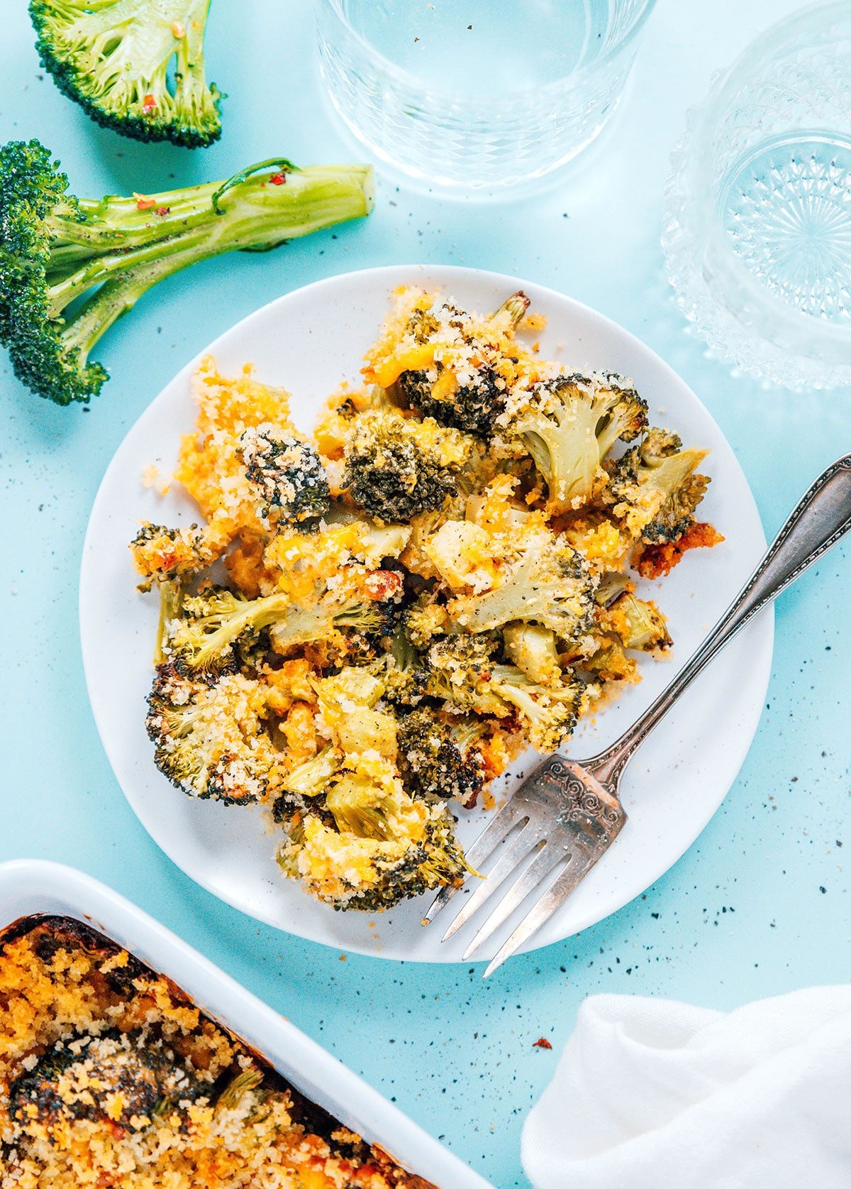 A serving of cheesy broccoli casserole on a small white plate with a fork.