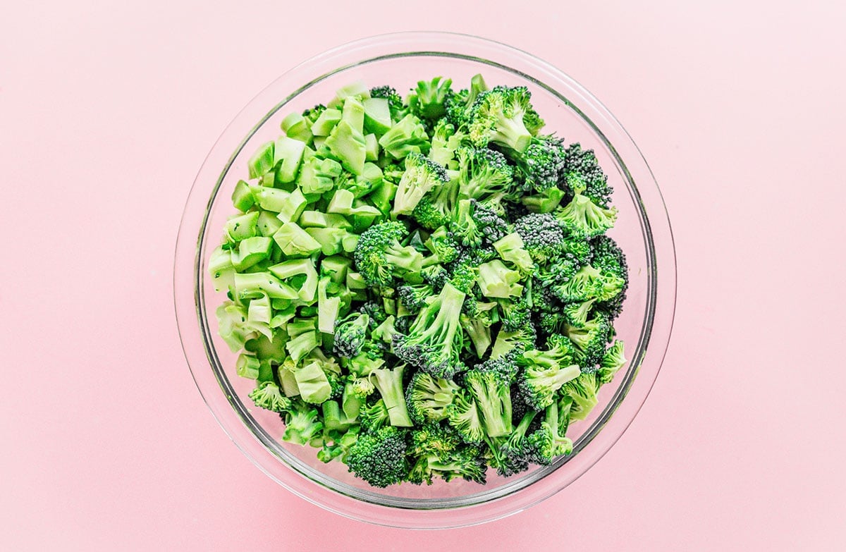A large glass mixing bowl filled with chopped fresh broccoli.