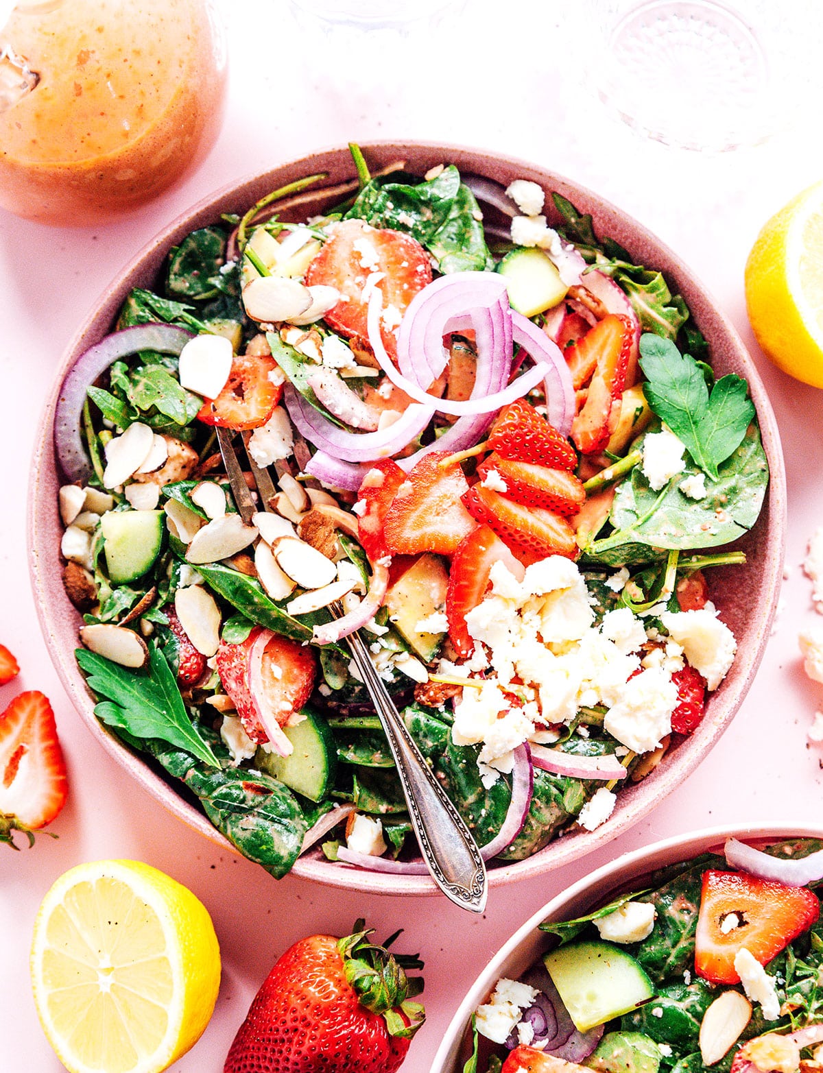Strawberry spinach salad in a large pink bowl with a salad serving fork.