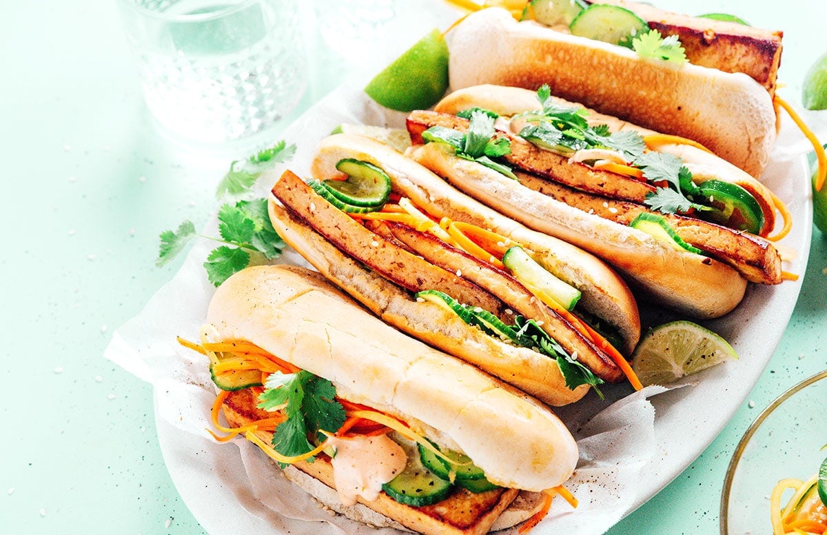A platter filled with 4 tofu banh mi sandwiches in row.