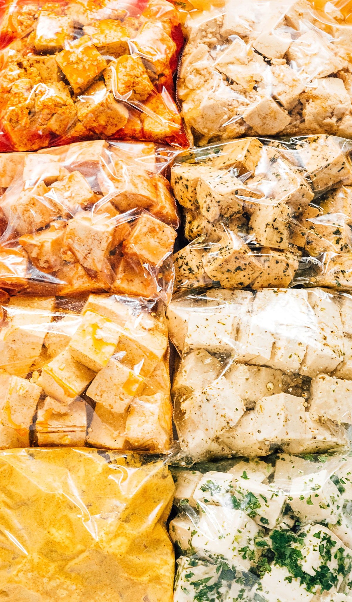 8 bags of tofu cubes in various colorful marinades.