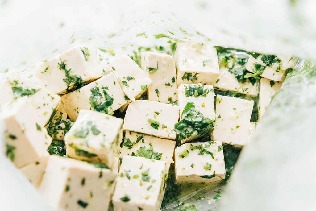 Cilantro lime marinade and tofu cubes are combined in a zip top bag.