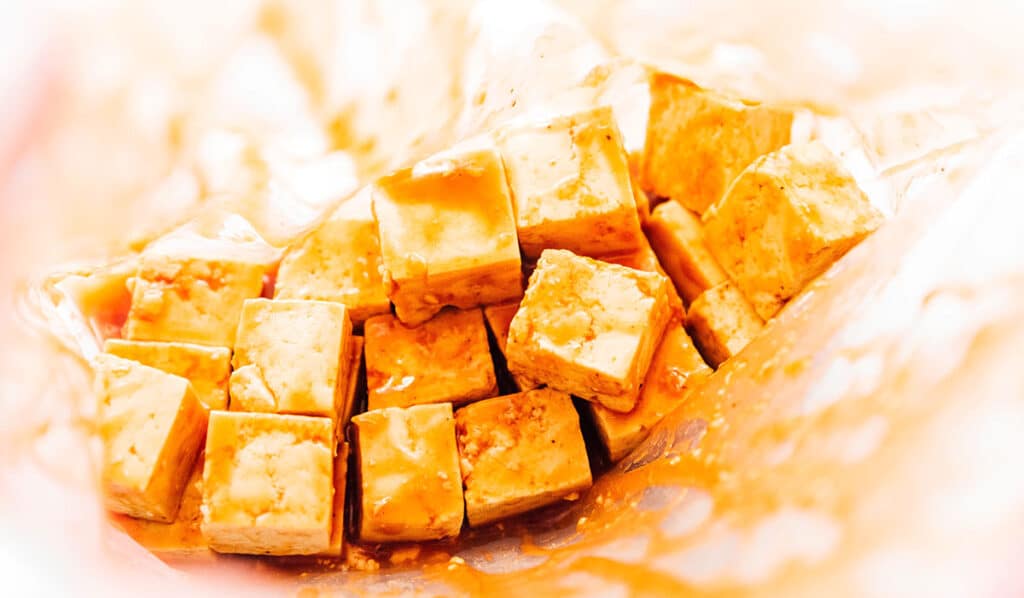 Tofu cubes and barbecue marinade in a zip top bag.