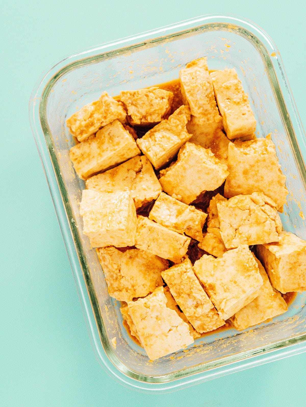 Tofu nuggets marinating in a small glass dish.