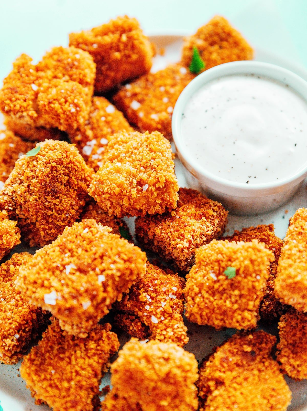 Breaded tofu nuggets on a platter with a small bowl of ranch dressing.