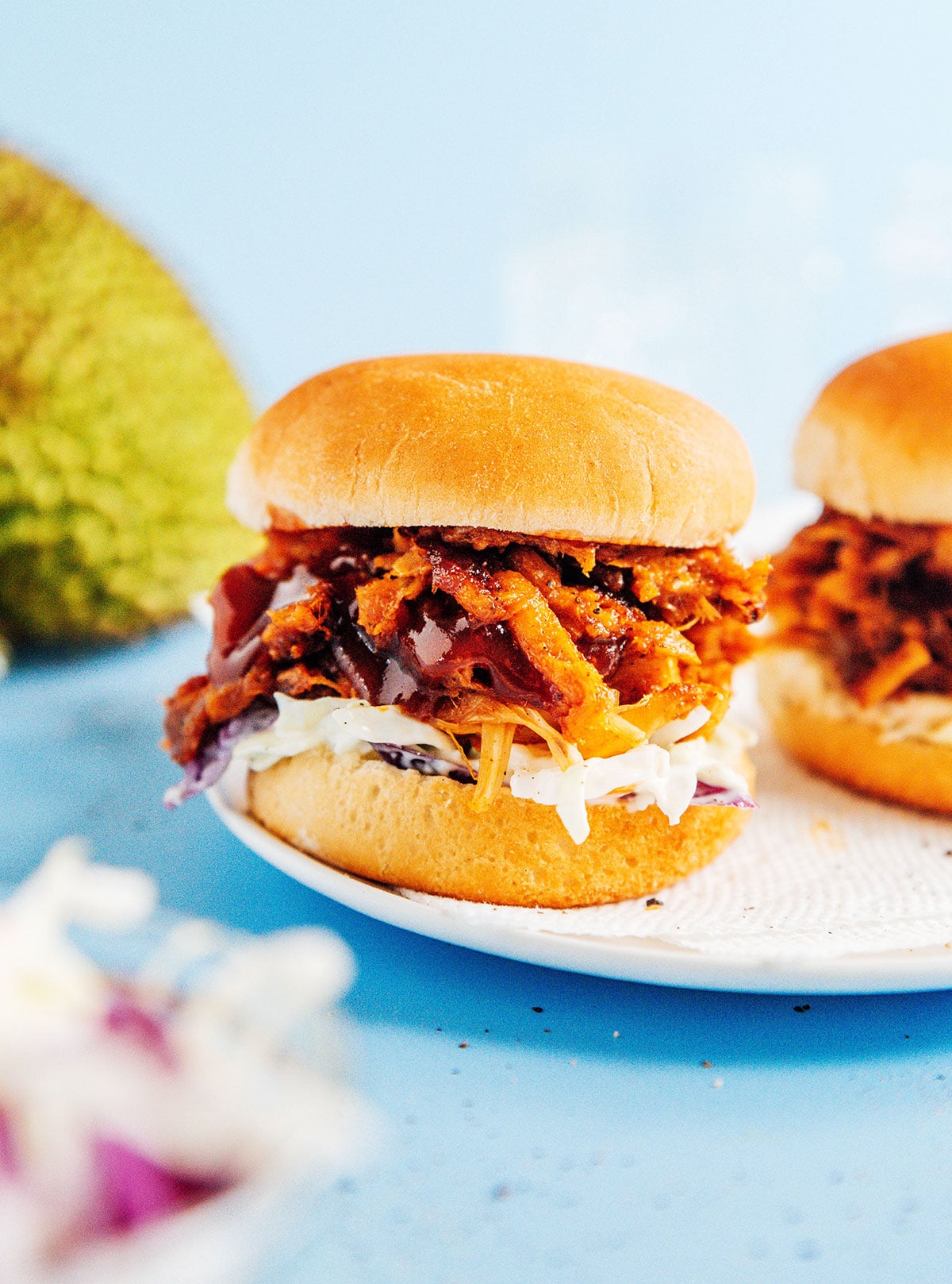 Up close image of bbq jackfruit slider with coleslaw and dripped bbq sauce.