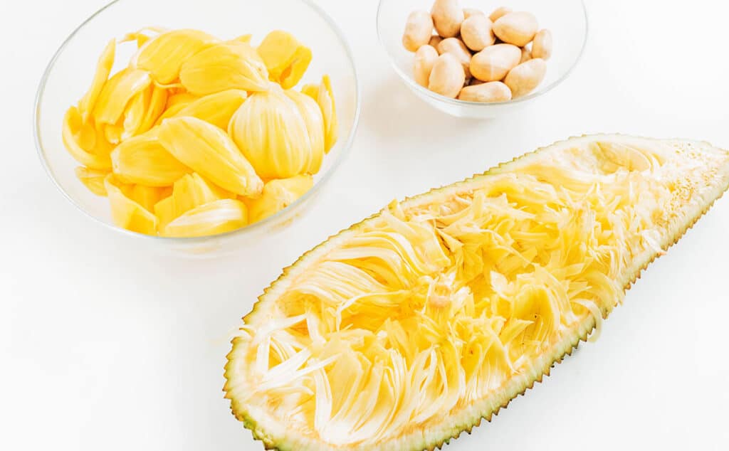 Jackfruit cut open with the yellow bulbs and seeds removed leaving a stringy inside in the rind.