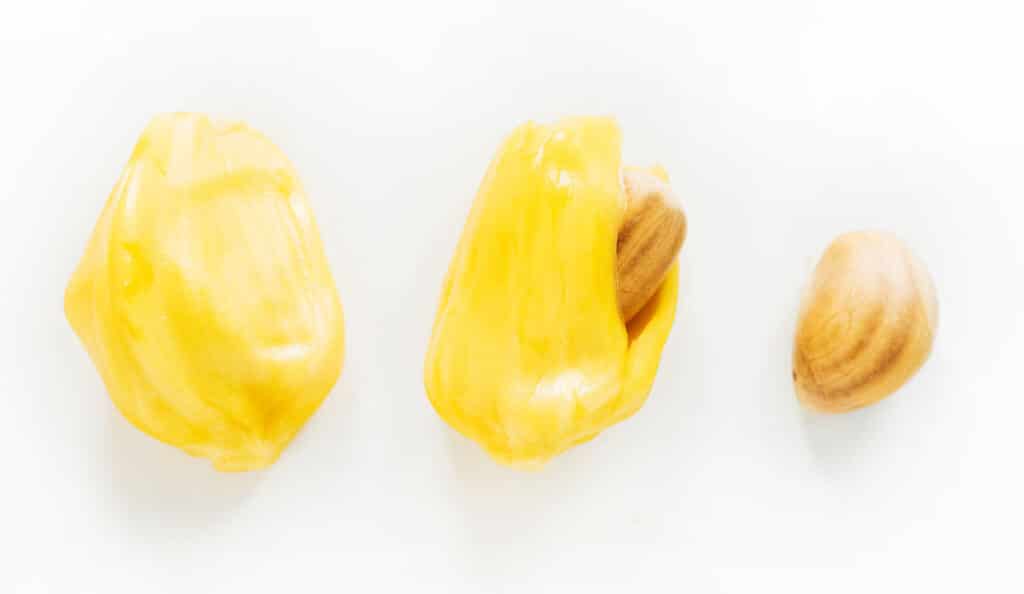 Two jackfruit bulbs next to each other showing the seed being removed.