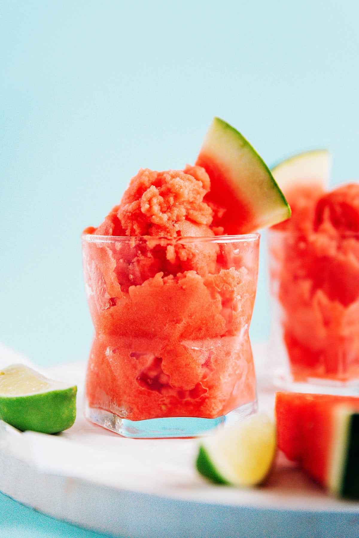 A short glass filled with watermelon sorbet and a small slice of watermelon.