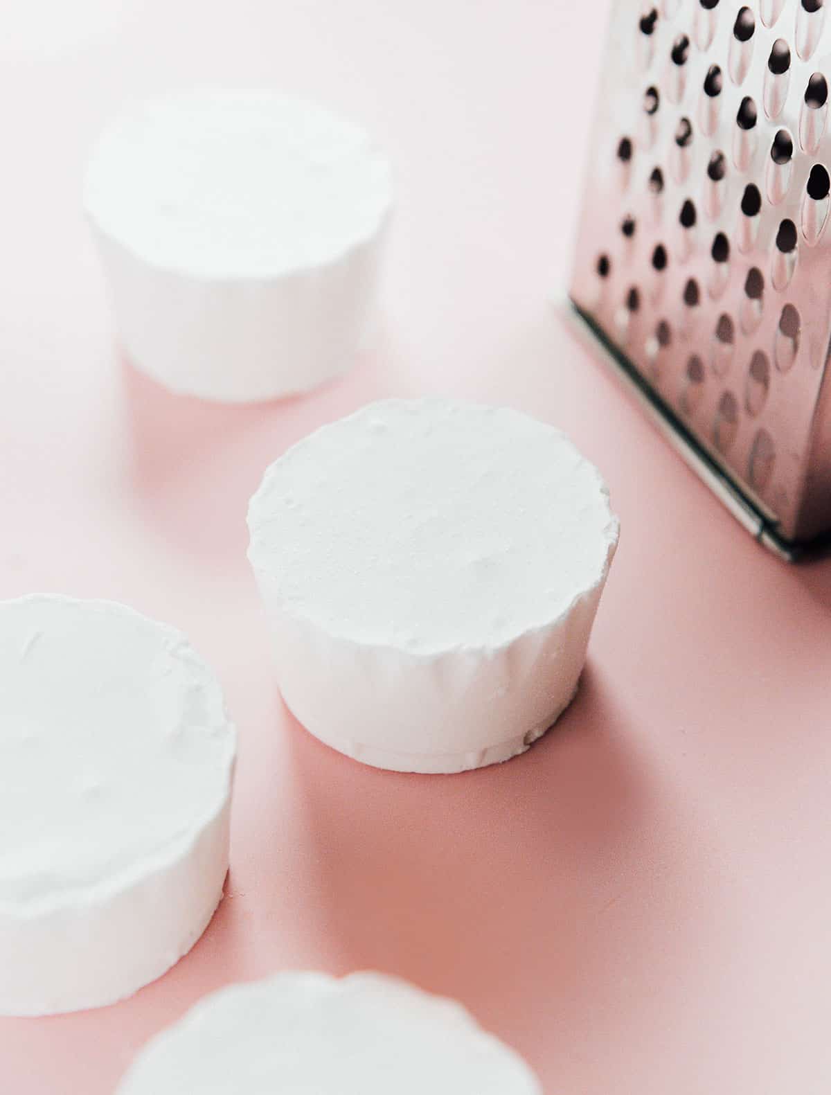 Coconut oil fat pucks on a pink surface.