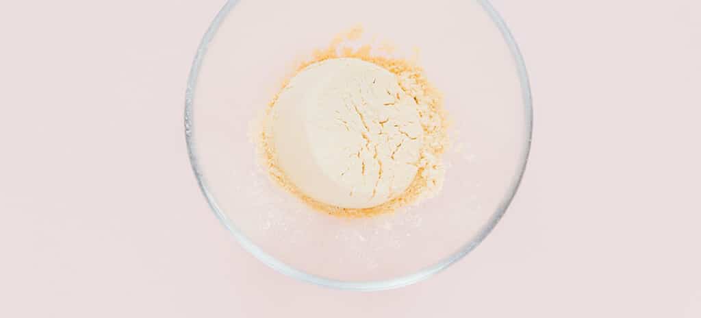 A small glass bowl of powdered pea protein.