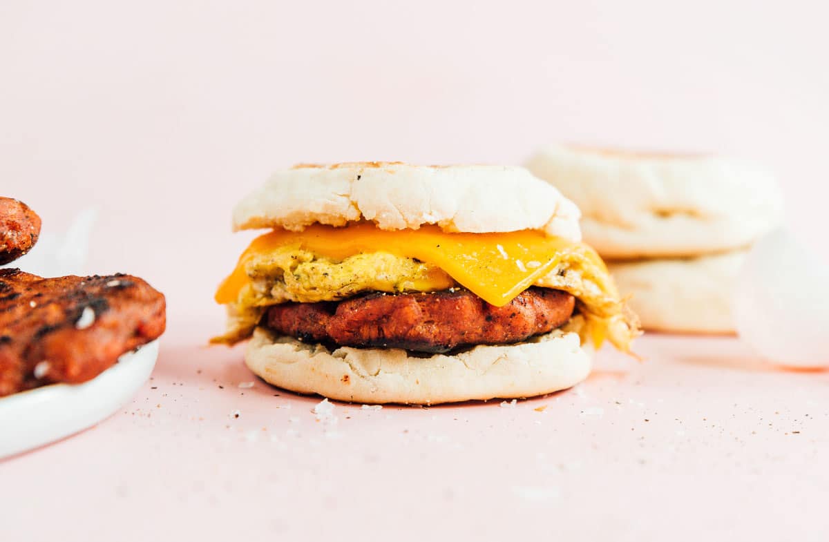 A breakfast sandwich consisting of english muffin, vegan sausage, with egg and cheese.