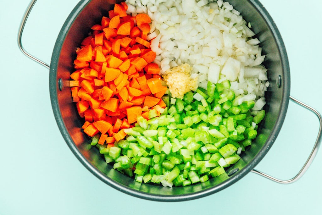 Celery, carrots, and onions in a pot.