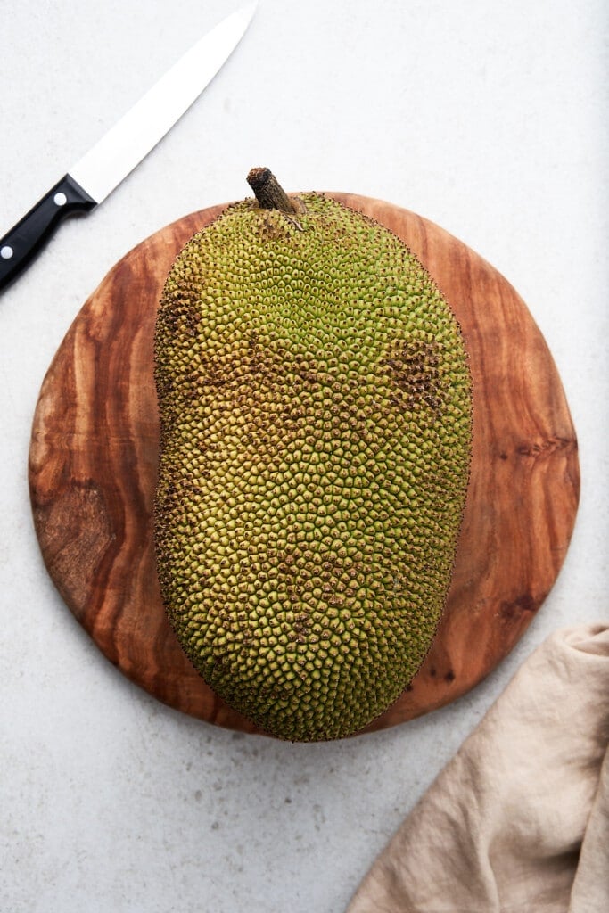 Jackfruit on a cutting board with a knife