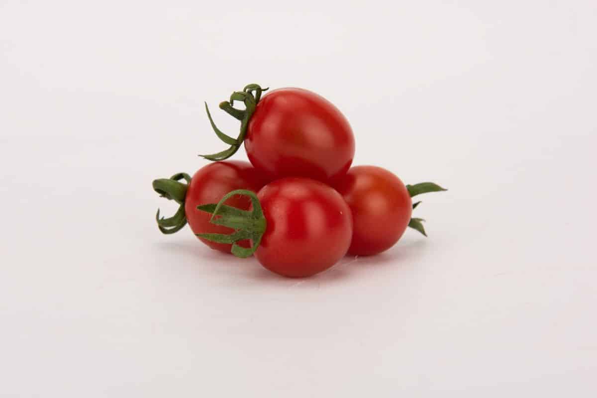Four cherry roma tomatoes on a white background.