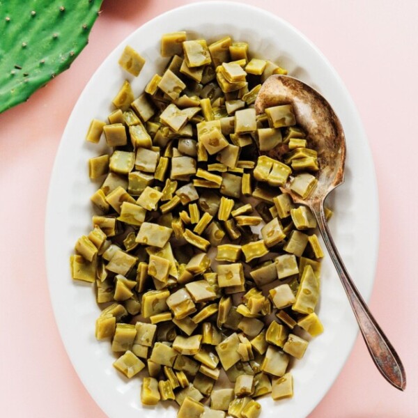 Diced cooked nopales on a white platter with a serving spoon