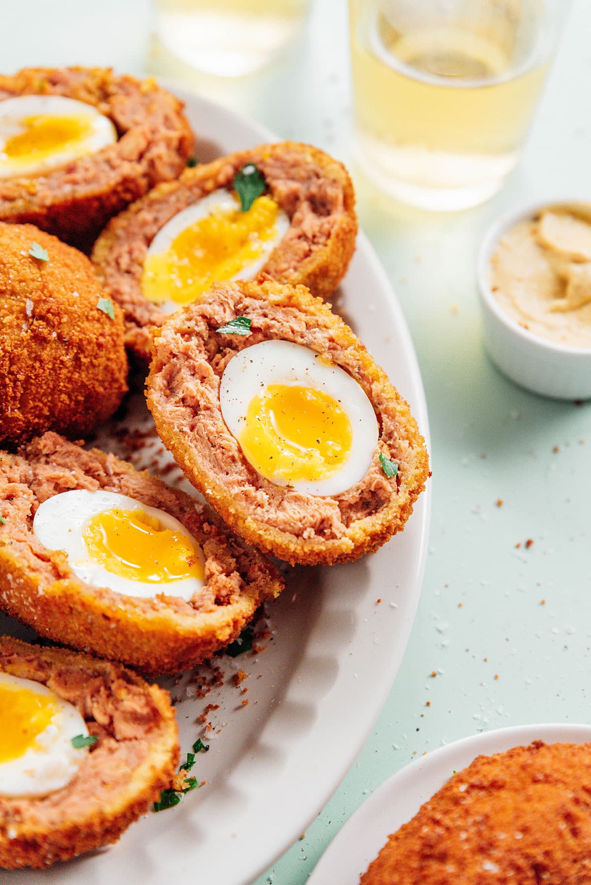 Cooked vegetarian scotch eggs on a white serving platter.