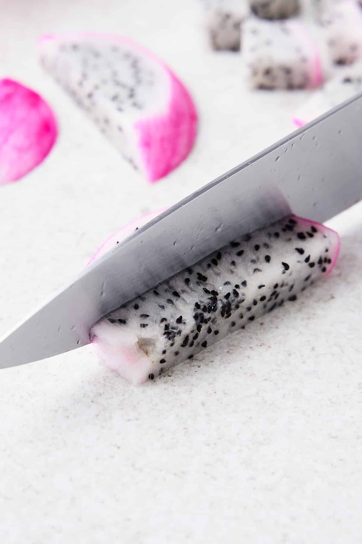 Knife cutting a piece of dragonfruit