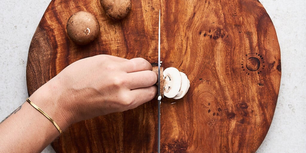 Option 2 - Sliced: Place the mushroom stem side down on your cutting board. Hold the mushroom in place with your non-dominant hand, making sure to press your knuckles towards the knife to protect your fingers. Slice the mushroom as thick or thin as you’d like, continuously edging your knuckle away from the knife as it moves closer.