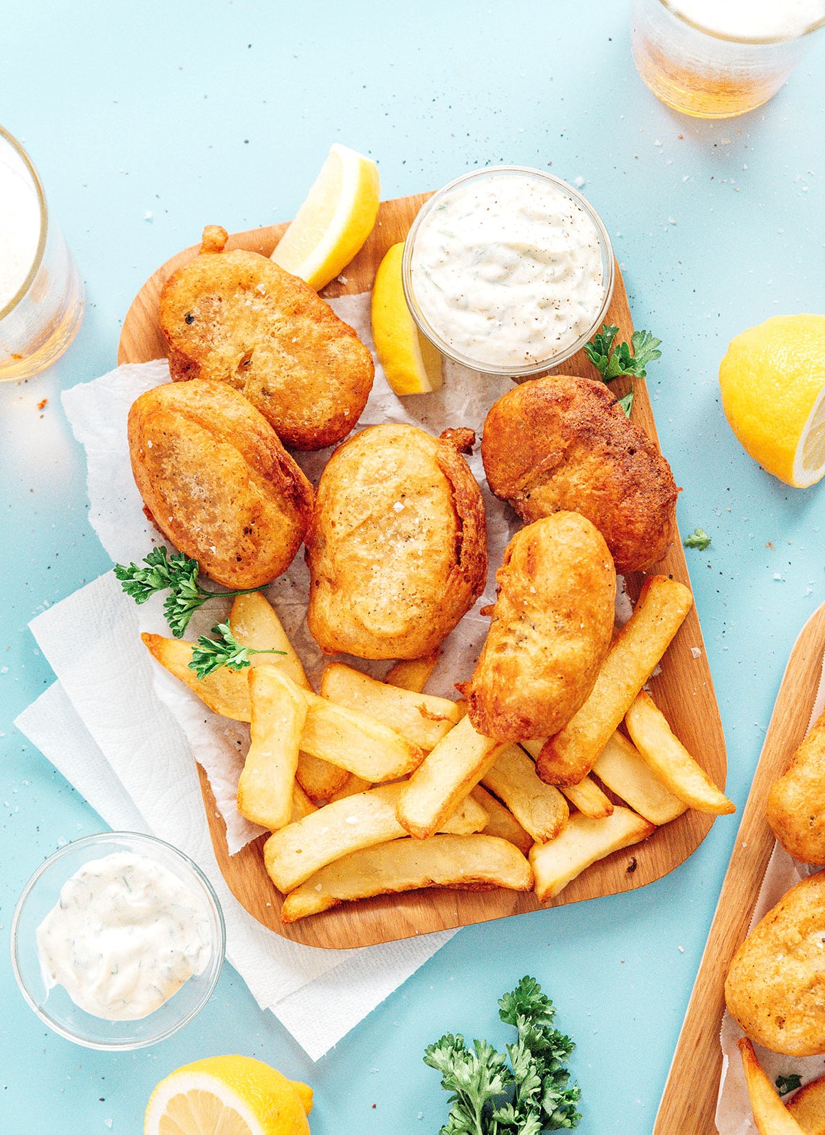 Vegan fish and chips on a wood board with a bowl of tartar sauce.