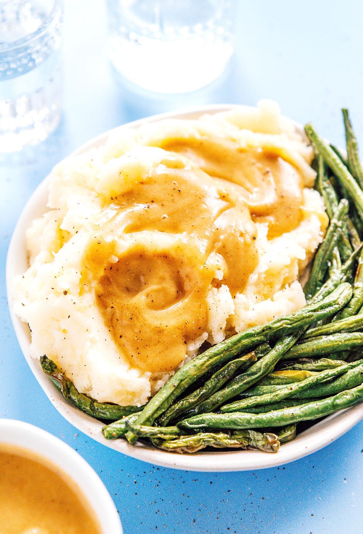 Mashed potatoes with green beans with vegan gravy on top.