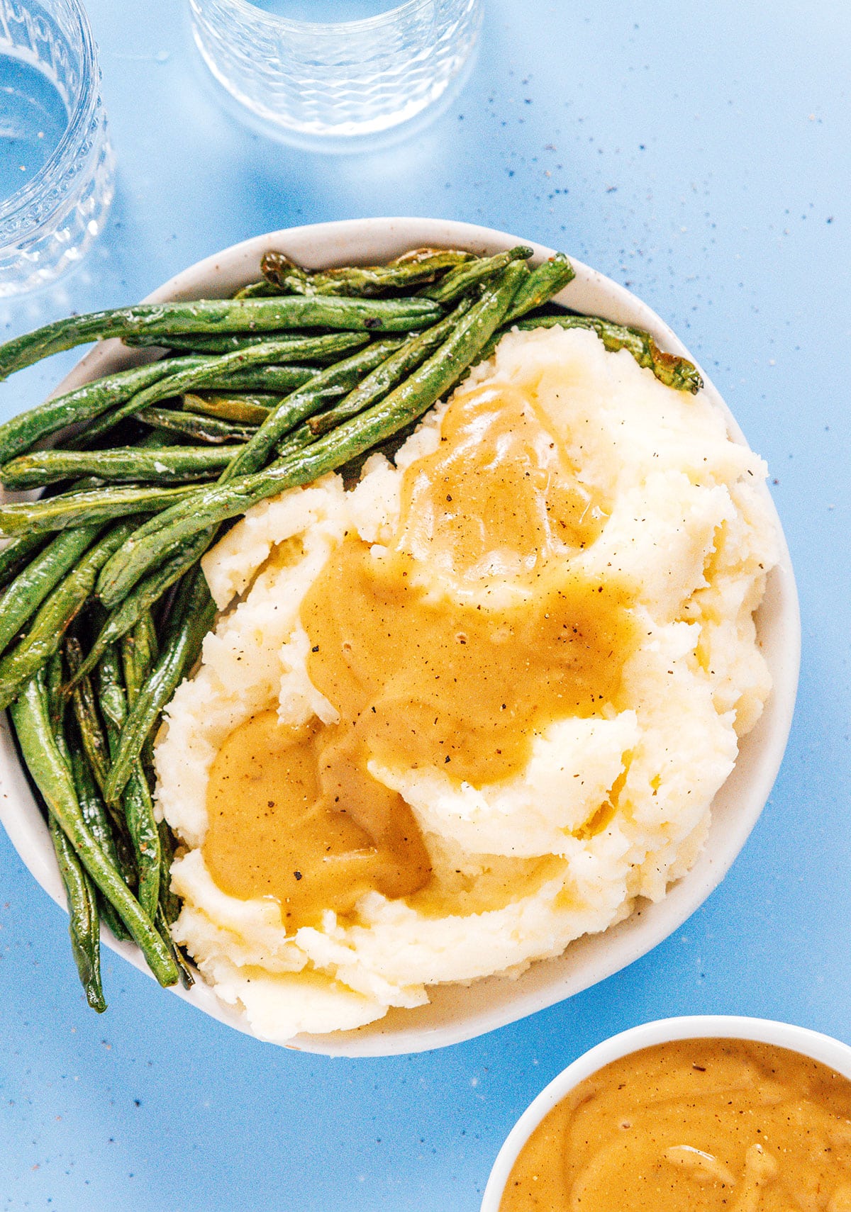 Mashed potatoes with green beans and gravy on top.