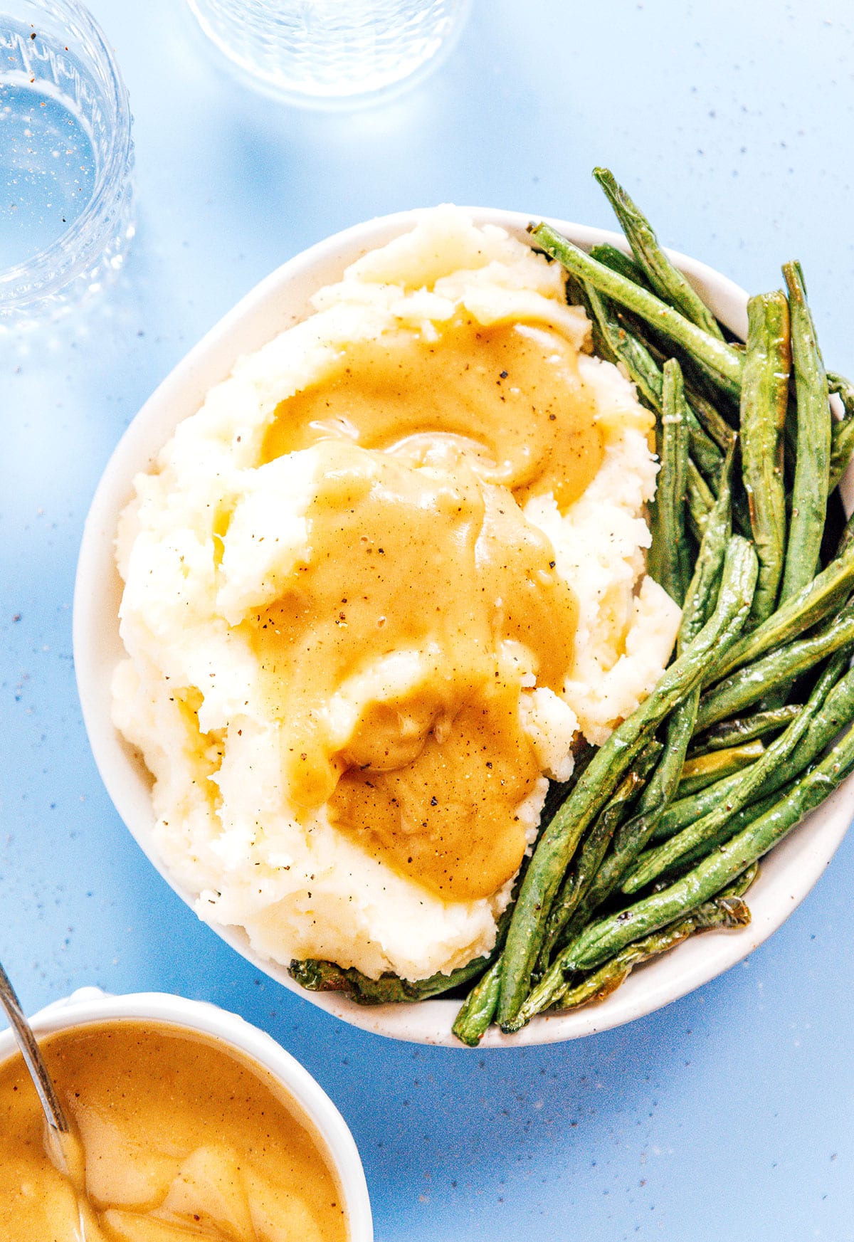 Gravy on top of mashed potatoes and green beans.