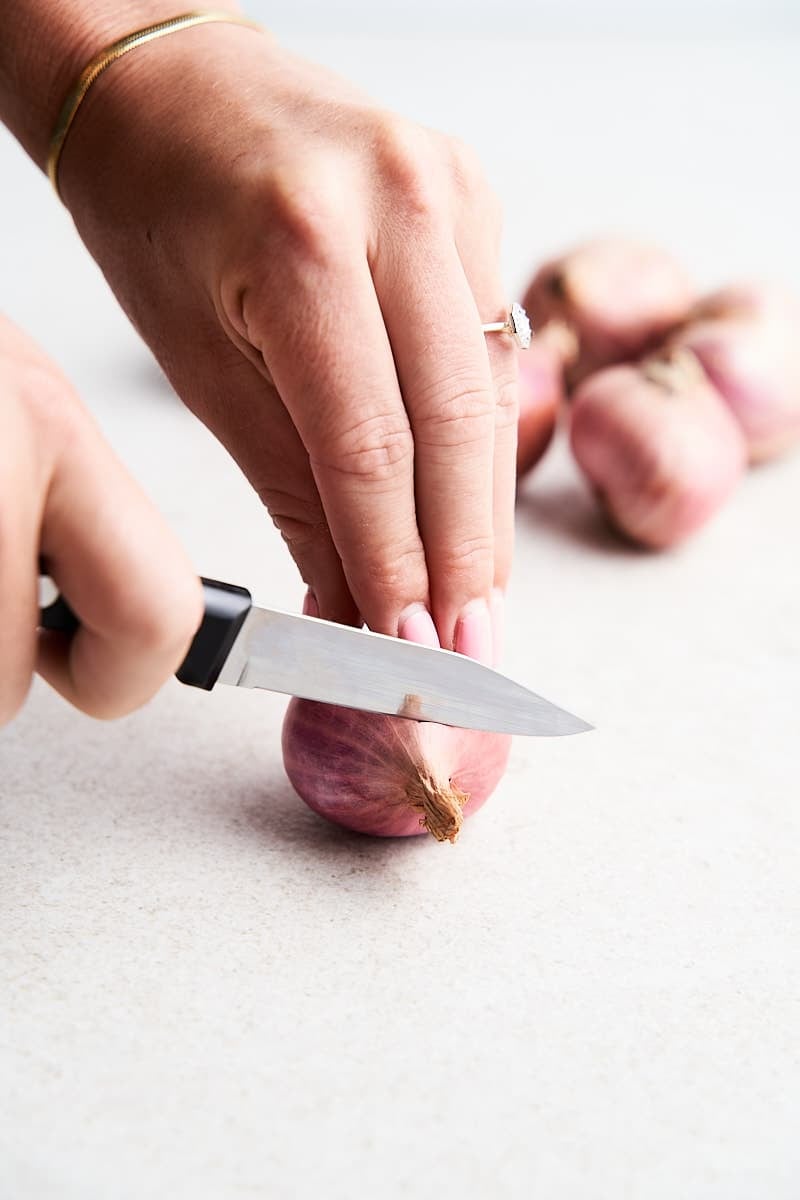 Cutting the top off of a shallot.
