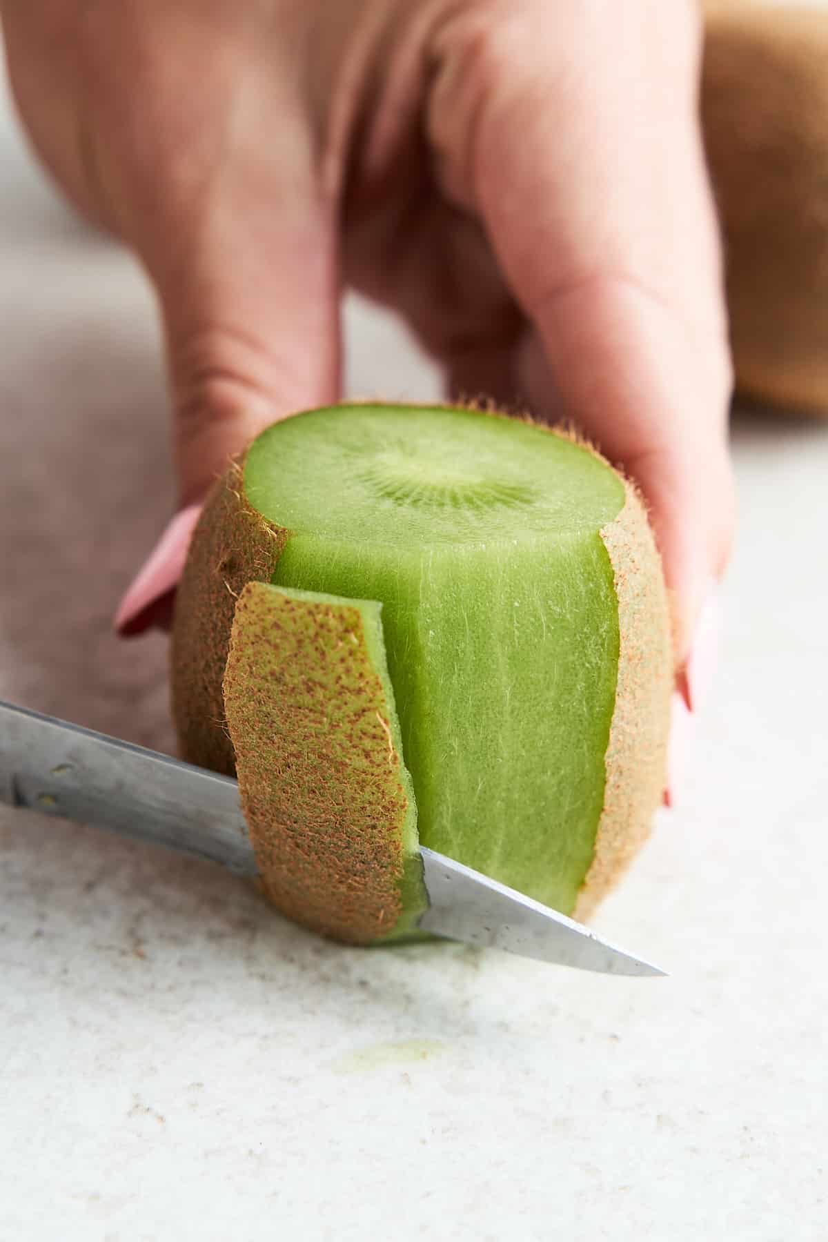 Cutting away the skin of a kiwi.